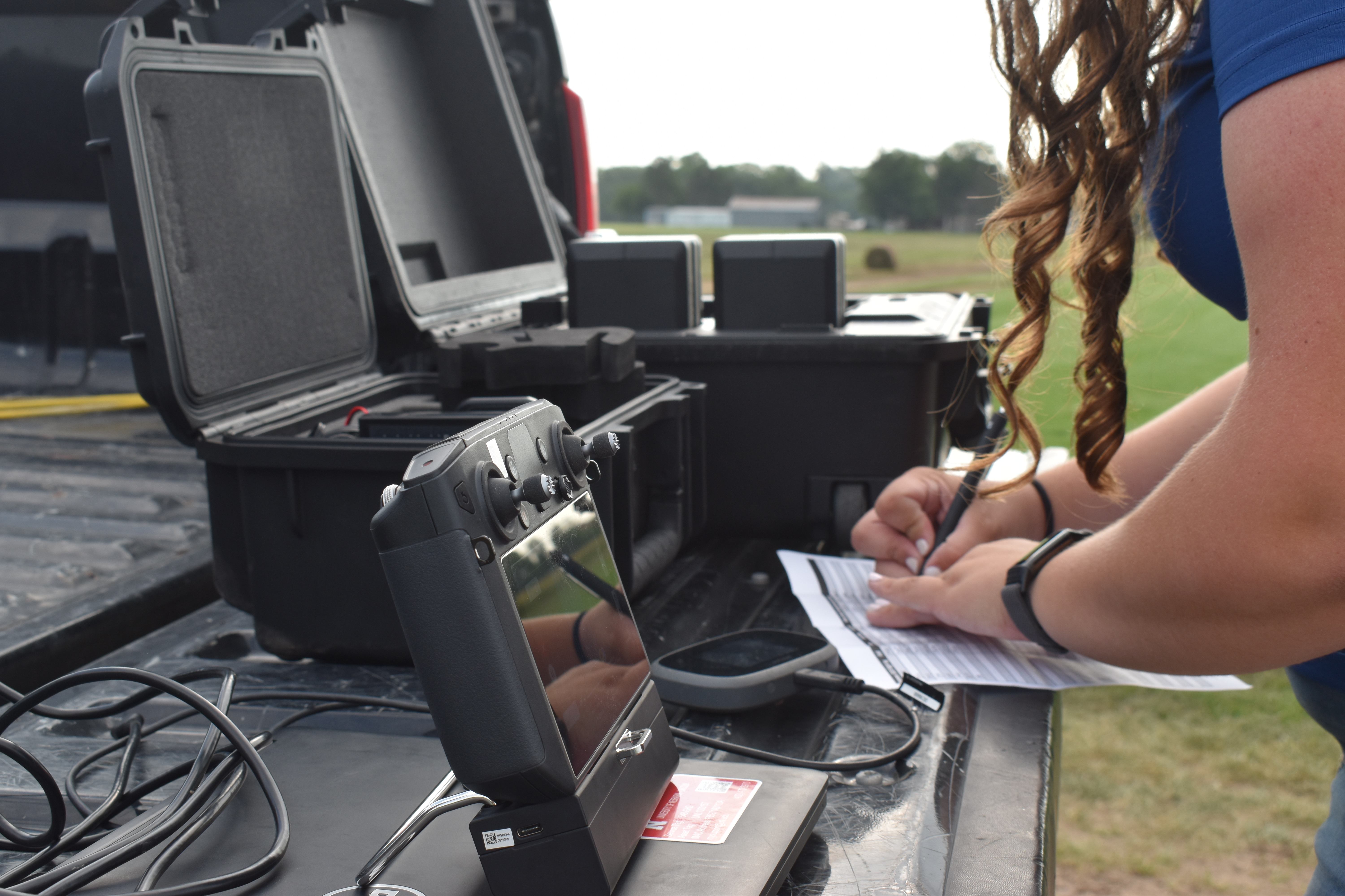Drone flight Equipment on a truck bed with ENREEC research tech taking notes a clipboard outdoors.